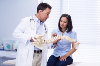 Physiotherapist explaining spine model to patient