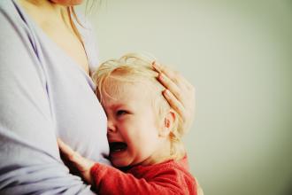 Distressed child crying in his mother's arms