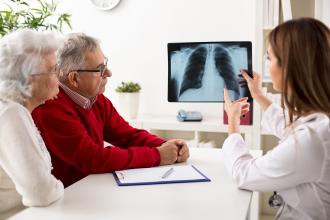 X-ray of lungs being shown to an elderly couple by a female doctor