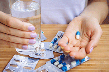 A patient holds an antibiotic and a glass of water