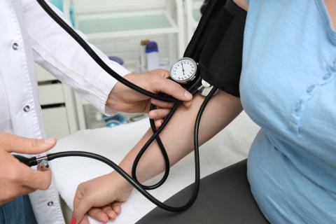 A doctor takes the blood pressure of an overweight patient