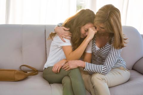 A mother comforts her teen daughter, who is upset