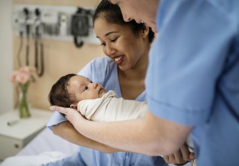 A couple holds their newborn baby in the maternity ward of a hospital