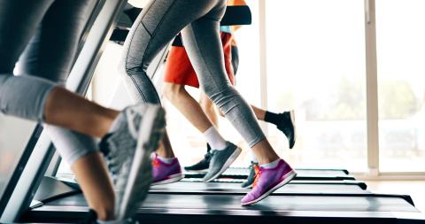 A group of people are running on treadmills at a gym