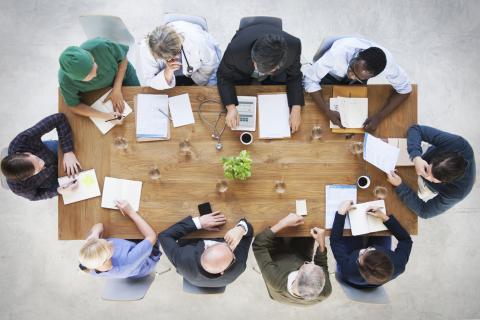 A top view of a medical team sitting around a boardroom table