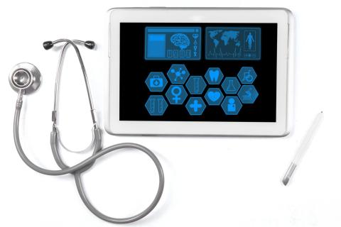 A stethoscope sits next to a tablet with medical icons on the screen