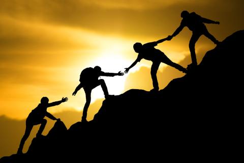 A team works together to climb a mountain