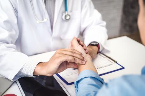 Doctor checking the pulse of a patient at desk