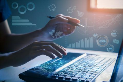 Hands typing on a laptop with chart graphics overlay