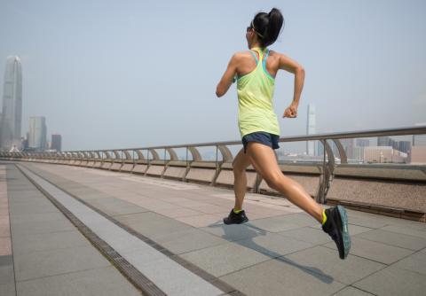 Female runner jogging with city and hazy sky in distance