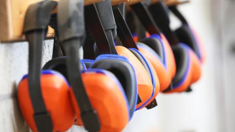 Row of orange protective earmuffs hanging on a rack