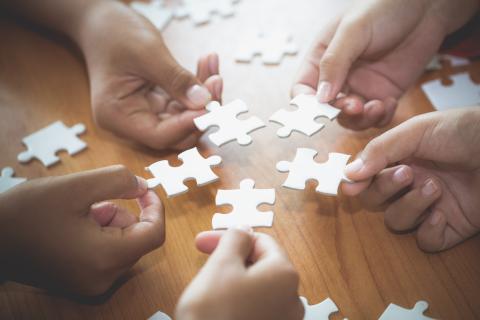 Hands are seen placing puzzle pieces together