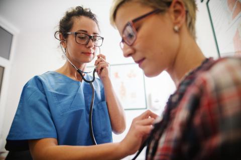 A doctor listens to a patient's chest using a stethoscope