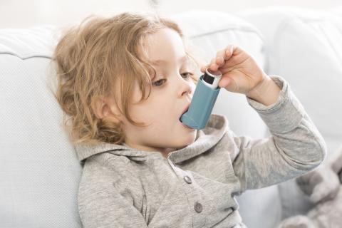 A young girl uses an inhaler
