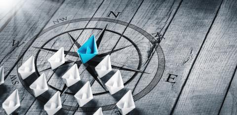 A group of paper boats with one in the lead