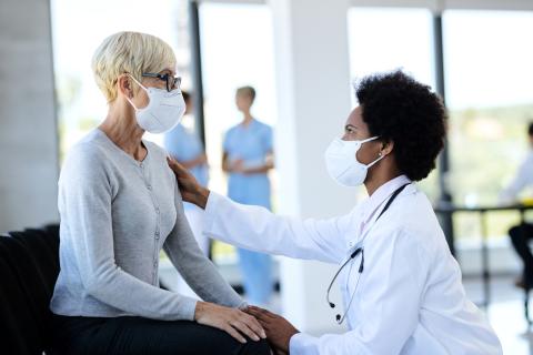A doctor talks to a patient who is sitting in a hallway in the hospital