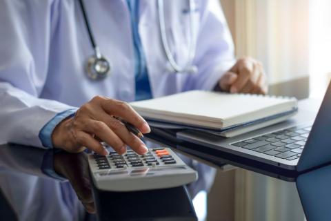 A doctor does paperwork using a calculator