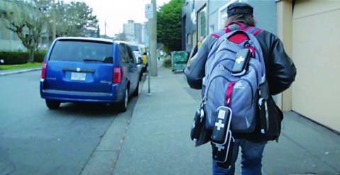 A man carries a backpack with Take Home Naloxone kits