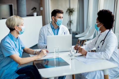 A team of doctors and administrators talk at a boardroom table