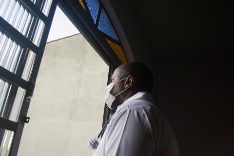A doctor wearing a mask looks out a window