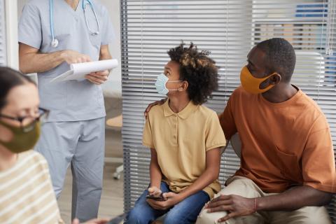 A doctor greets a teen and his dad in the waiting area