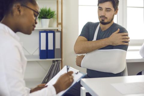 A man with a cast on his arm talks to his doctor