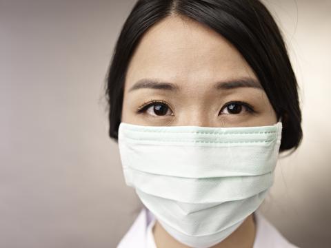 An Asian health care worker wearing a mask