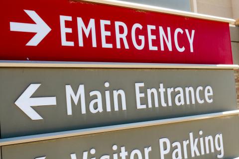 A sign outside a hospital with an arrow pointing to the emergency department