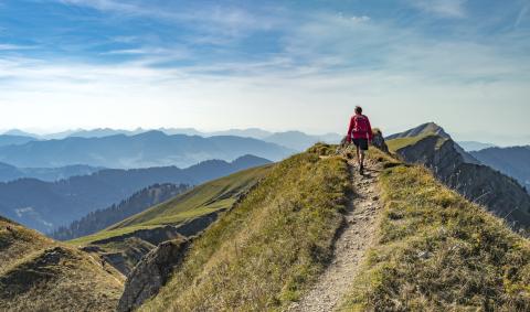 A backpacker stands at the top of a mountain, looking around