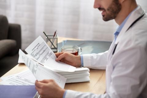 A doctor is reviewing a stack of medical reports.