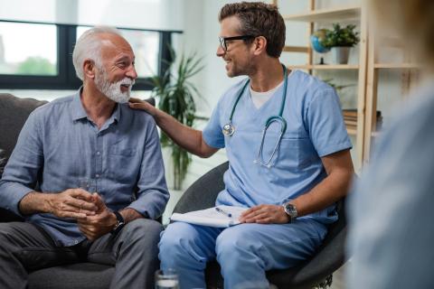 A doctor talks with a senior patient in their home.