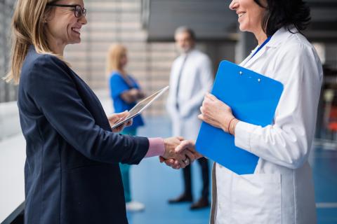 A doctor and a person in a suit shake hands.