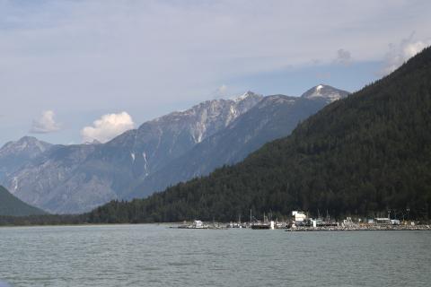 A remote town on the water with mountains in the background.