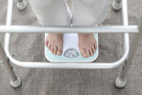 A person using a walker stands on the scale.