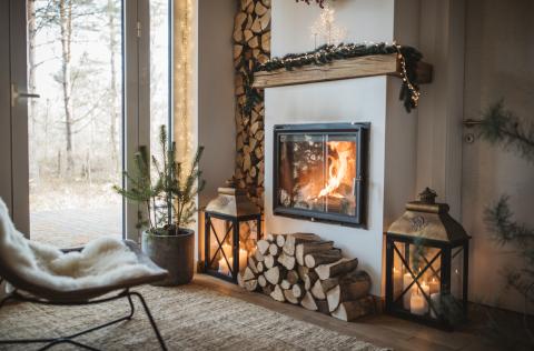A cozy chair with a blanket in front of a fireplace.
