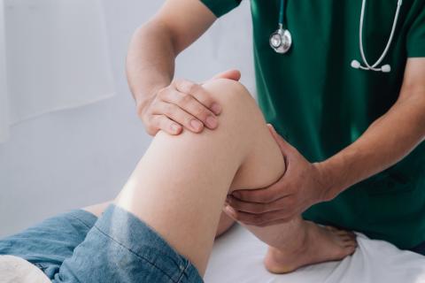 A doctor examines a patient’s knee.