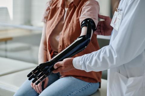 A doctor helps a patient use a prosthetic arm.