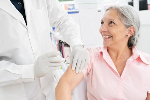 A pharmacist gives a senior a vaccination.