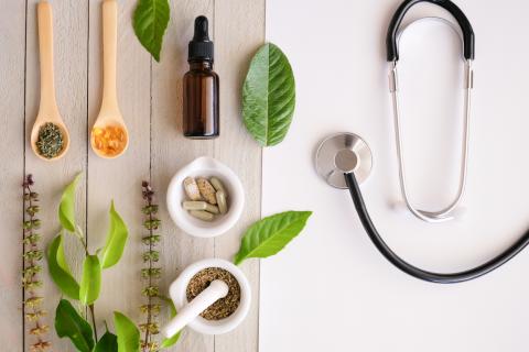 A selection of herbal and traditional medicines on one side and a stethoscope on the other side.