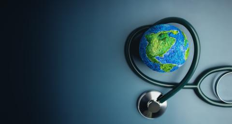 A stethoscope is curved in a heart shape around a globe.