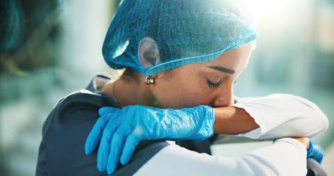 A surgeon sits on the floor, with their hands wrapped around their knees.