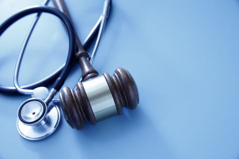 A stethoscope is wrapped around a gavel.