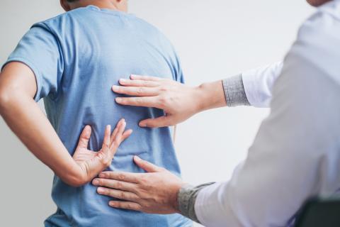 A doctor examines a patient’s back.