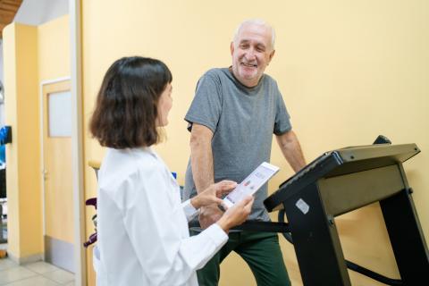 A doctor talks to a patient walking on a treadmill.
