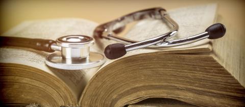 A stethoscope sits on top of an old medical textbook