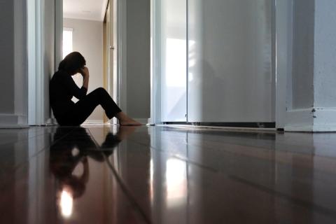 A teenager sits in a hallway, head down