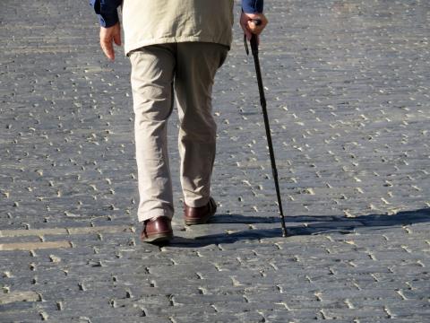 A senior man walks with a cane