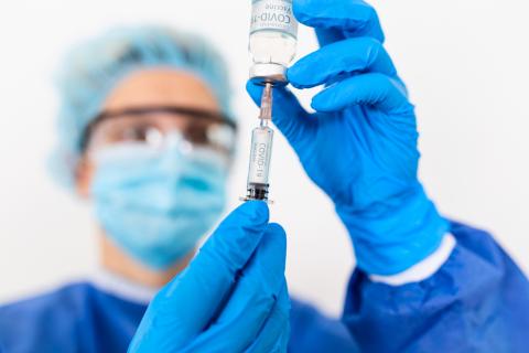 A doctor prepares a syringe with the COVID-19 vaccine