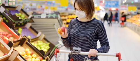 A woman shops for groceries with a mask on