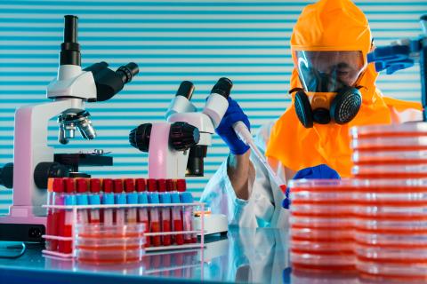 Research Of dangerous viruses in the laboratory. Prevention of a pandemic. A scientist in a biological protective suit works with a pipette